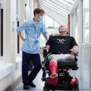 Photo of HCA Lewis with a patient in electric wheelchair