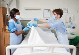 Photo of healthcare assistant and nurse making a bed